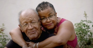 Older black man and black woman embracing each other. 