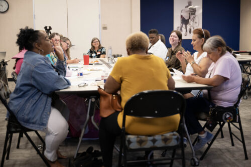 Individuals sitting at a table at the listening session in Dallas, TX with the Senior Source